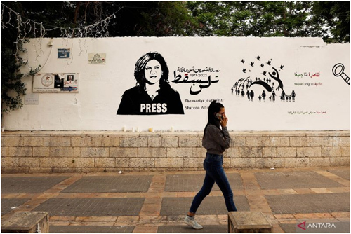 Warga melintas dekat grafiti bagi jurnalis Shireen Abu Akleh di Nazareth, Israel, Senin (16/5/2022). Shireen terbunuh saat militer Israel menyerbu Tepi Barat. (ant/rtr)