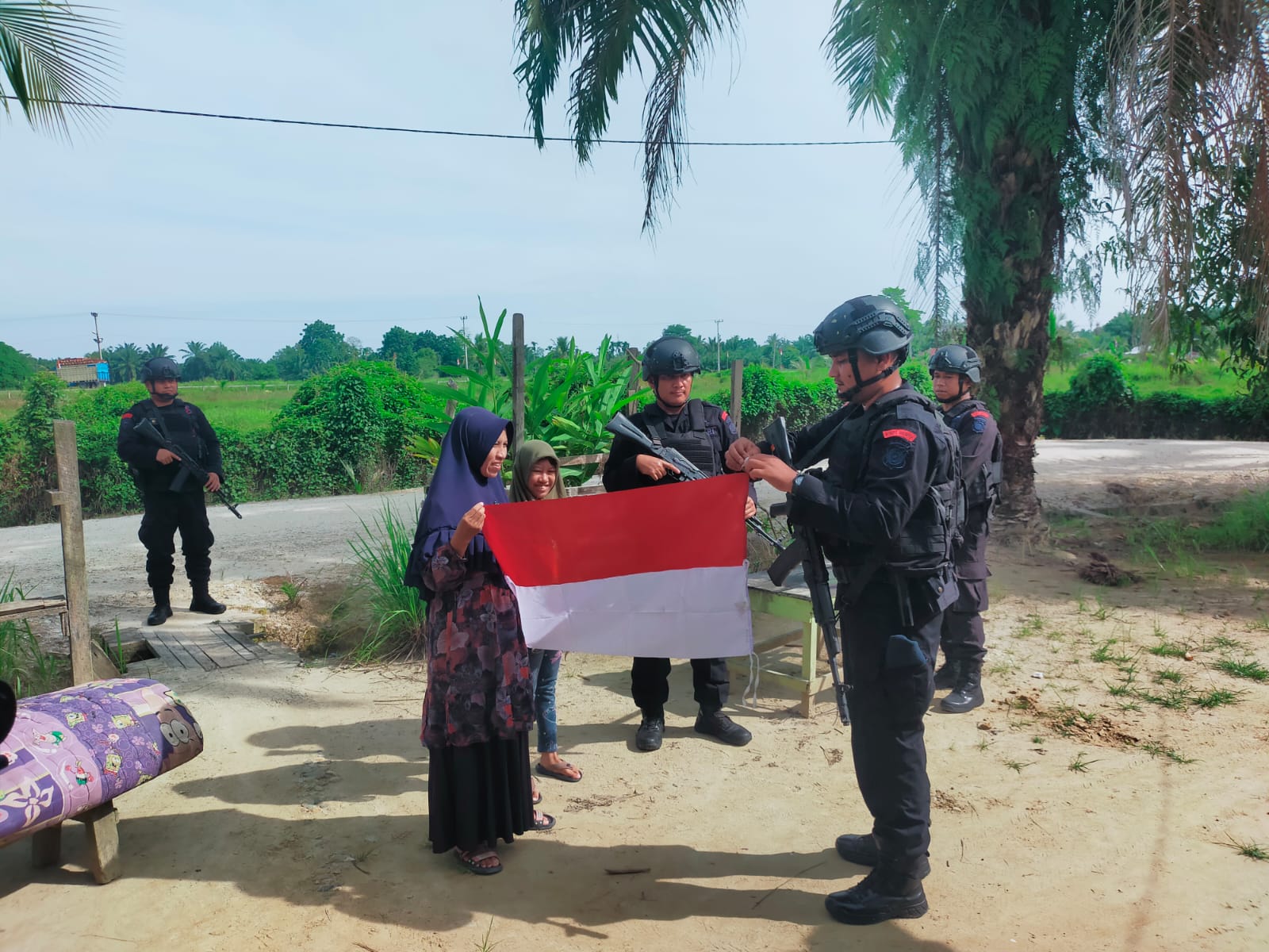 Personil Brimob Kompi 2 Batalyon B Pelopor Aramiyah saat membagikan bendera Merah Putih kepada warga, di Desa Alue Itam, Kecamatan Birem Bayeun, Kabupaten Aceh Timur, Senin (7/8). Foto: Rapian