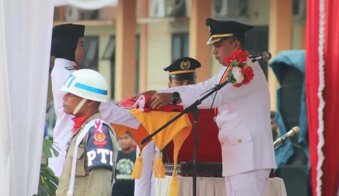 Teks Foto : Bupati Paluta Andar Amin Harahap, S.STP., M.Si. memberikan Bendera Merah Putih Kepada Paskibra Untuk dikibarkan.