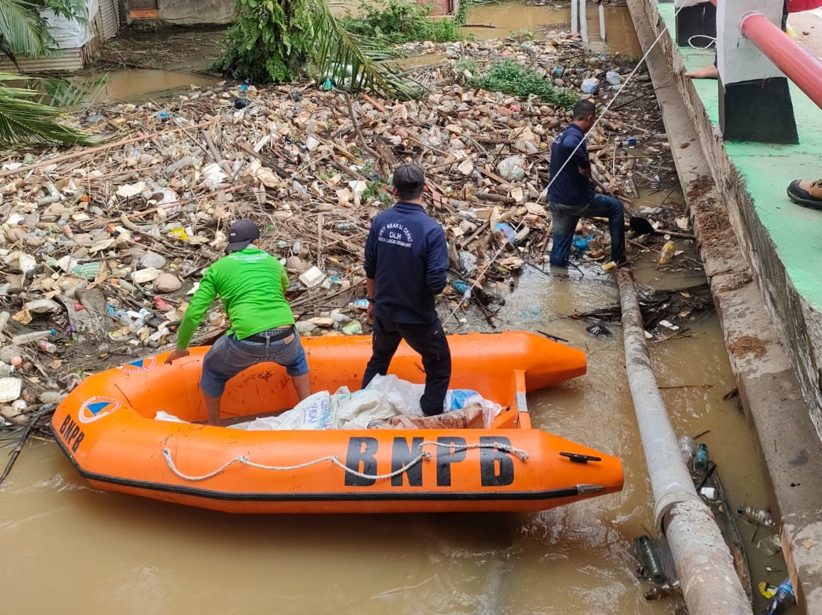 Teks Foto: Petugas sedang membersihkan saluran drainase di Lhokseumawe yang dipenuhi sampah plasti sehingga aliran air tersumbat