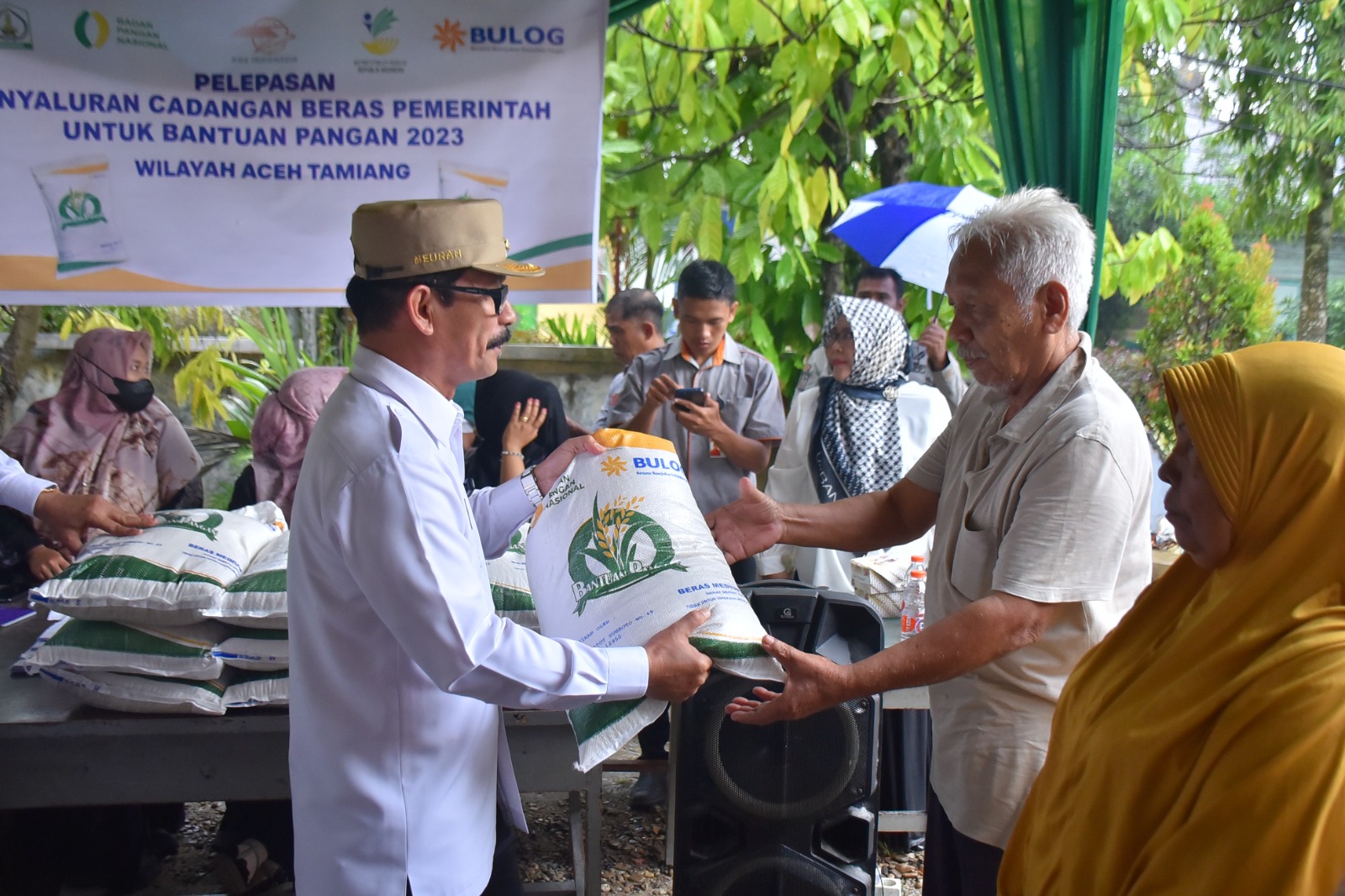 Teks foto : Penjabat (Pj) Bupati Aceh Tamiang, Dr. Drs. Meurah Budiman, SH, MH saat menyerahkan secara simbolis Bantuan Penyaluran Cadangan Beras Pemerintah di Halaman Kantor Pos Kota Kualasimpang, Rabu (20/9).