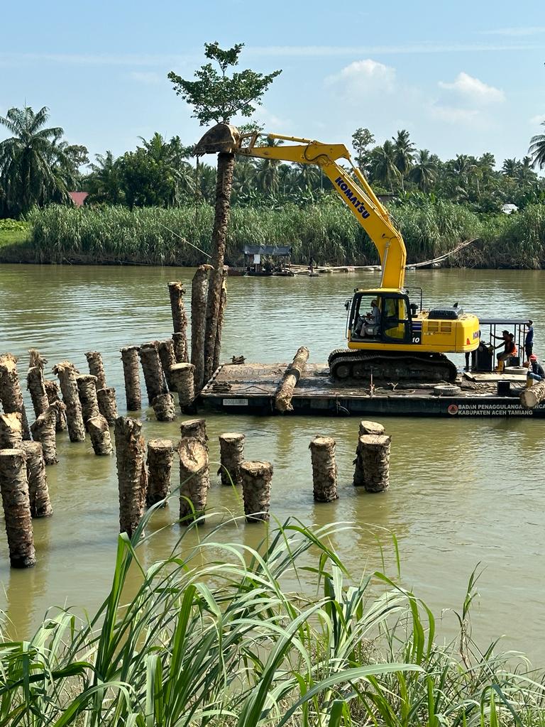 Teks foto : Alat berat jenis Excavator saat melakukan pemancangan batang kelapa sawit dari tebing sungai Pekan Seruway, Kecamatan Seruway, Kabupaten Aceh Tamiang.