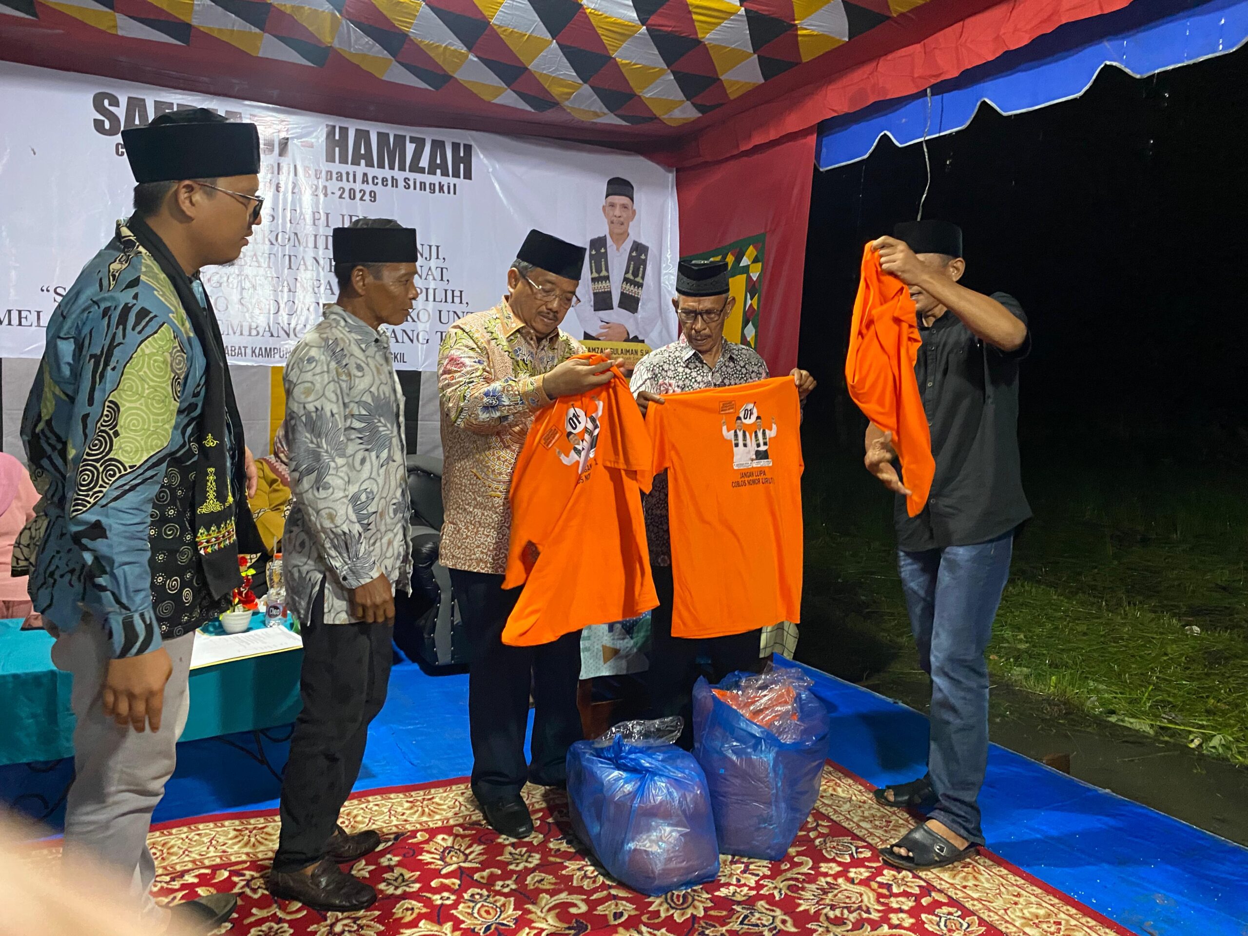 Ket photo, Perwakilan masyarakat desa Kilangan, kecamatan Singkil, menyerahkan 100 pcs kostum berlogo ‘Sahabat’ ke pasangan calon bupati, Safriadi Manik dan wakil nya, Hamzah Sulaiman, saat acara silaturahmi, jumat malam, 27 September 2024. M. Zaelani Sidik- berita sore